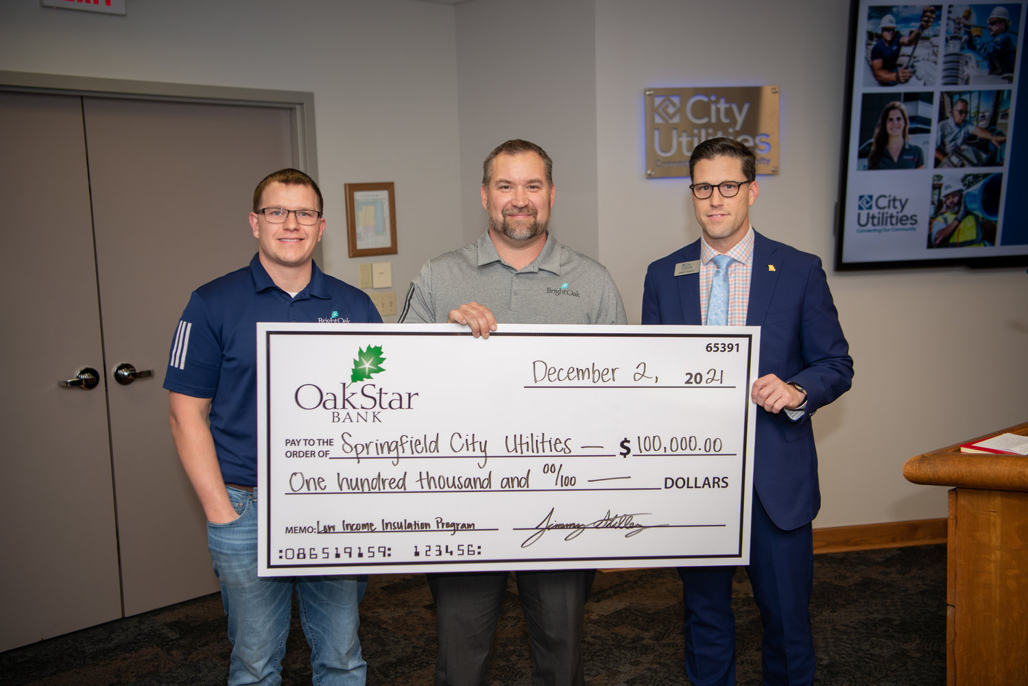 Adam Stipanovich and Jimmy Stilley of OakStar Bank’s BrightOak division deliver a $100,000 check to CU Chief Customer Officer Brent Baker.